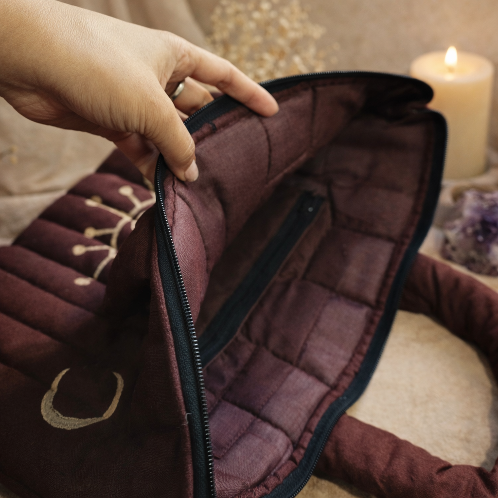 Close-up of a hand opening a quilted brown jacket with a blurred indoor background