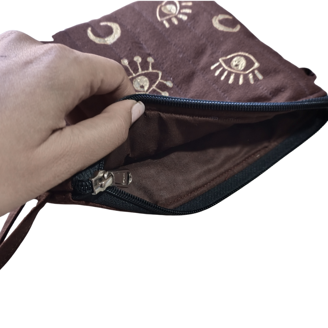 Hand holding a brown clutch with decorative patterns on a white background