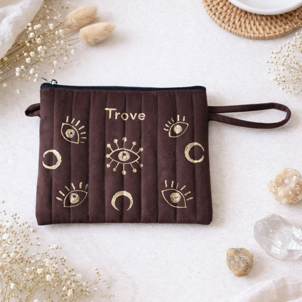 Brown pouch with gold designs and 'Trove' branding on a light background