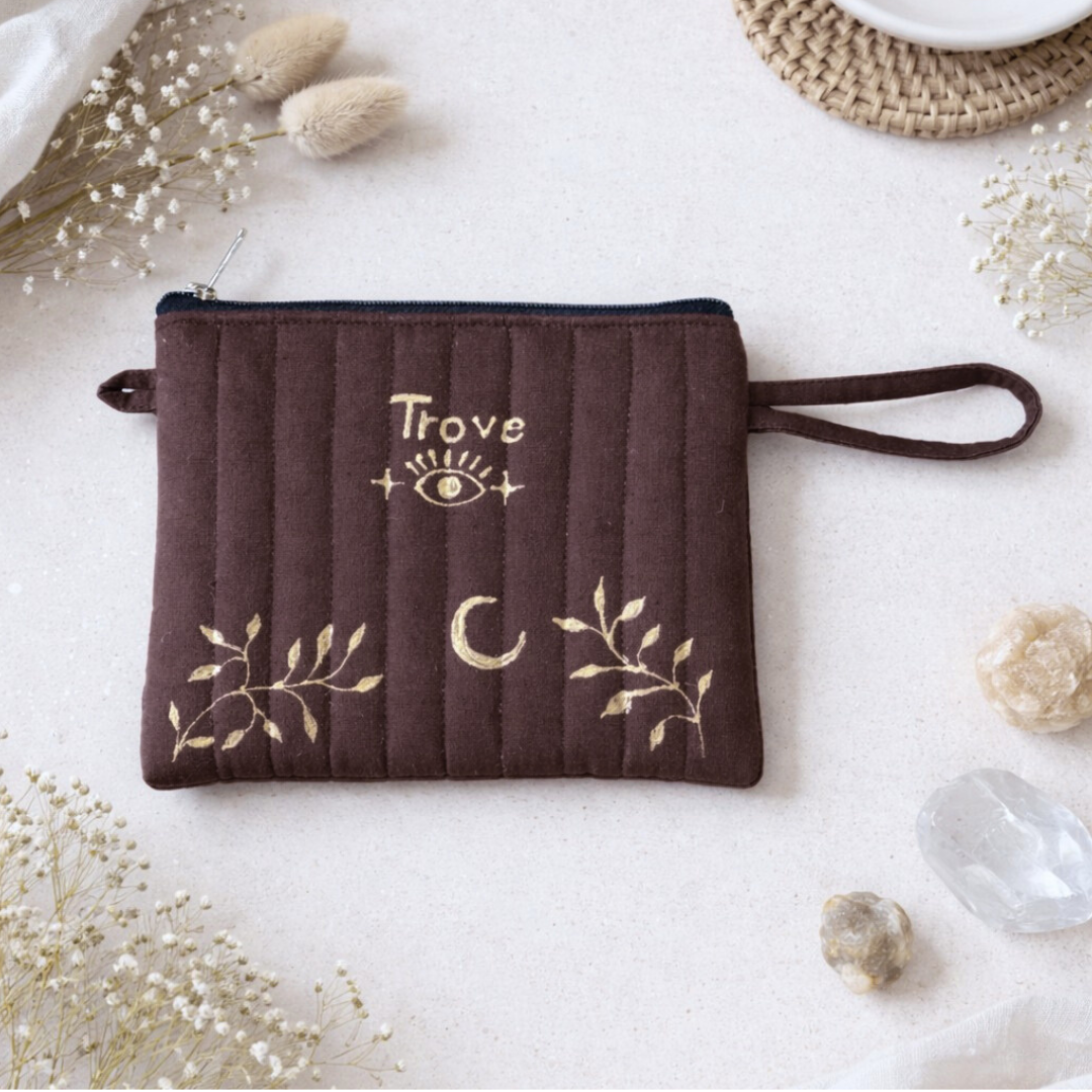 Brown pouch with 'Trove' branding and decorative elements on a light background