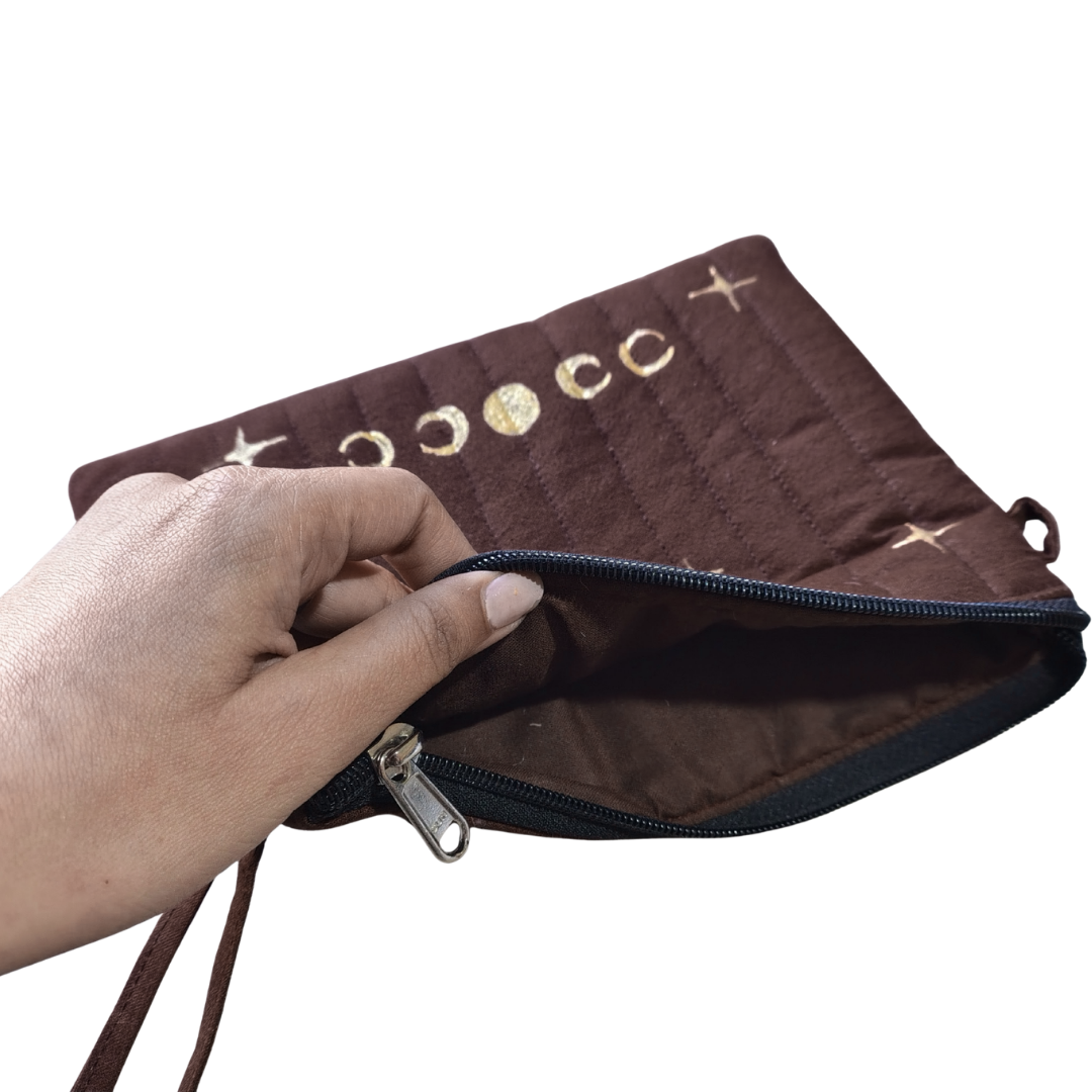Brown pouch with gold moon painted held by a hand.  bag for travelling 