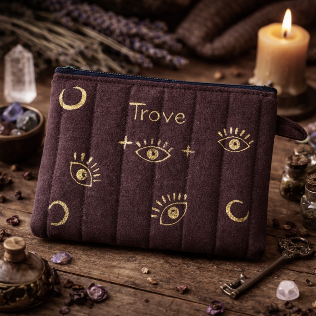Brown pouch with gold designs and 'Trove' branding on a mystical background with candles and crystals.