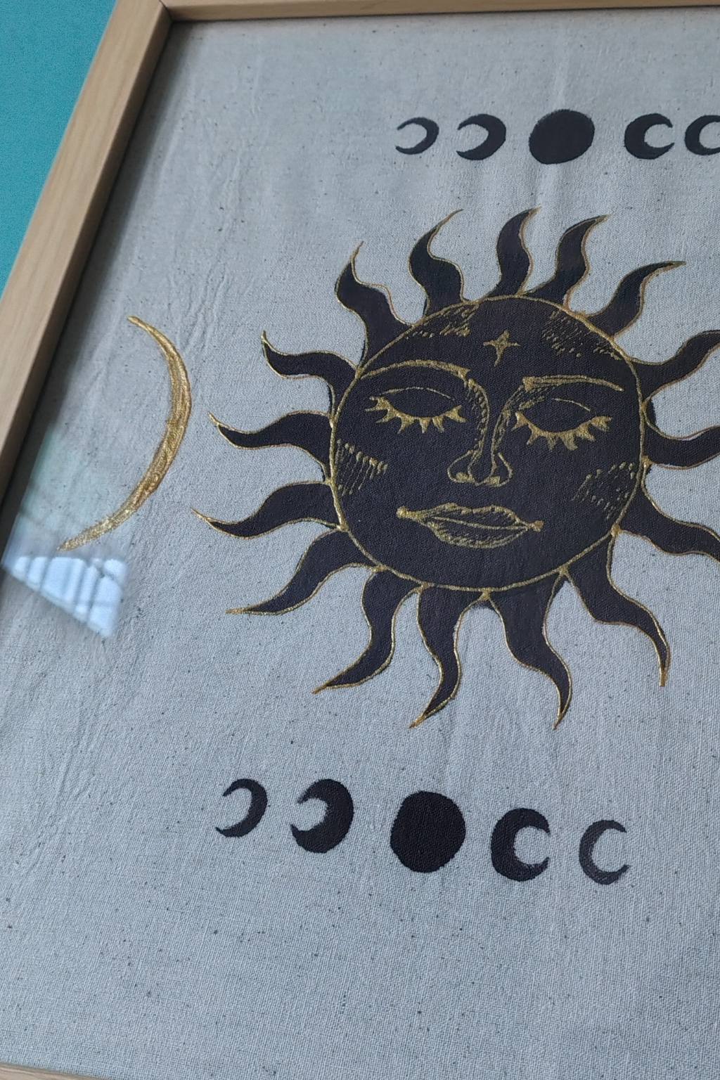 Decorative sun and moon design on a textured surface with a wooden frame.