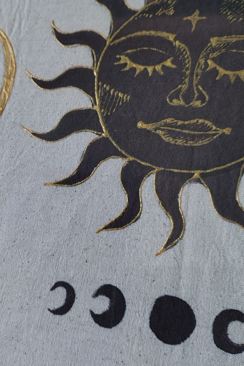 Decorative design of a sun face and moon phases on a textured fabric background