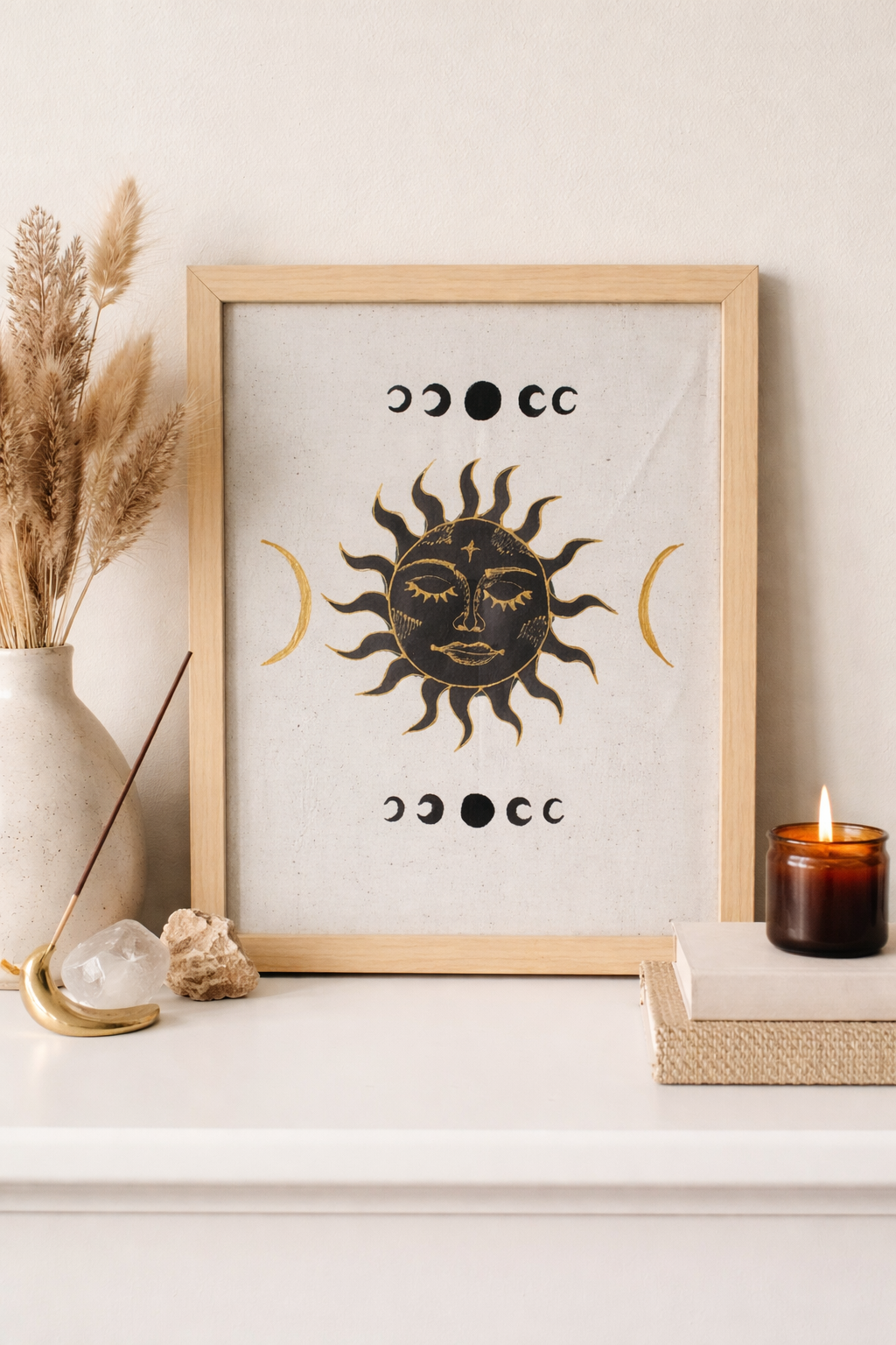 Framed artwork with sun and moon design on a white surface with decorative items.