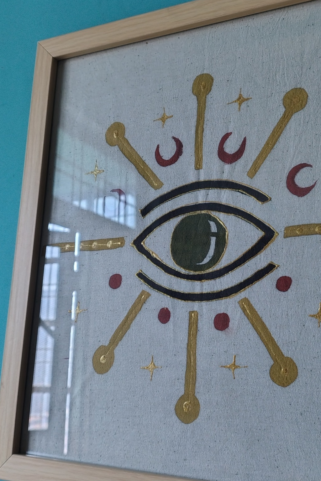 Decorative wall art with an eye design and celestial symbols in a wooden frame.