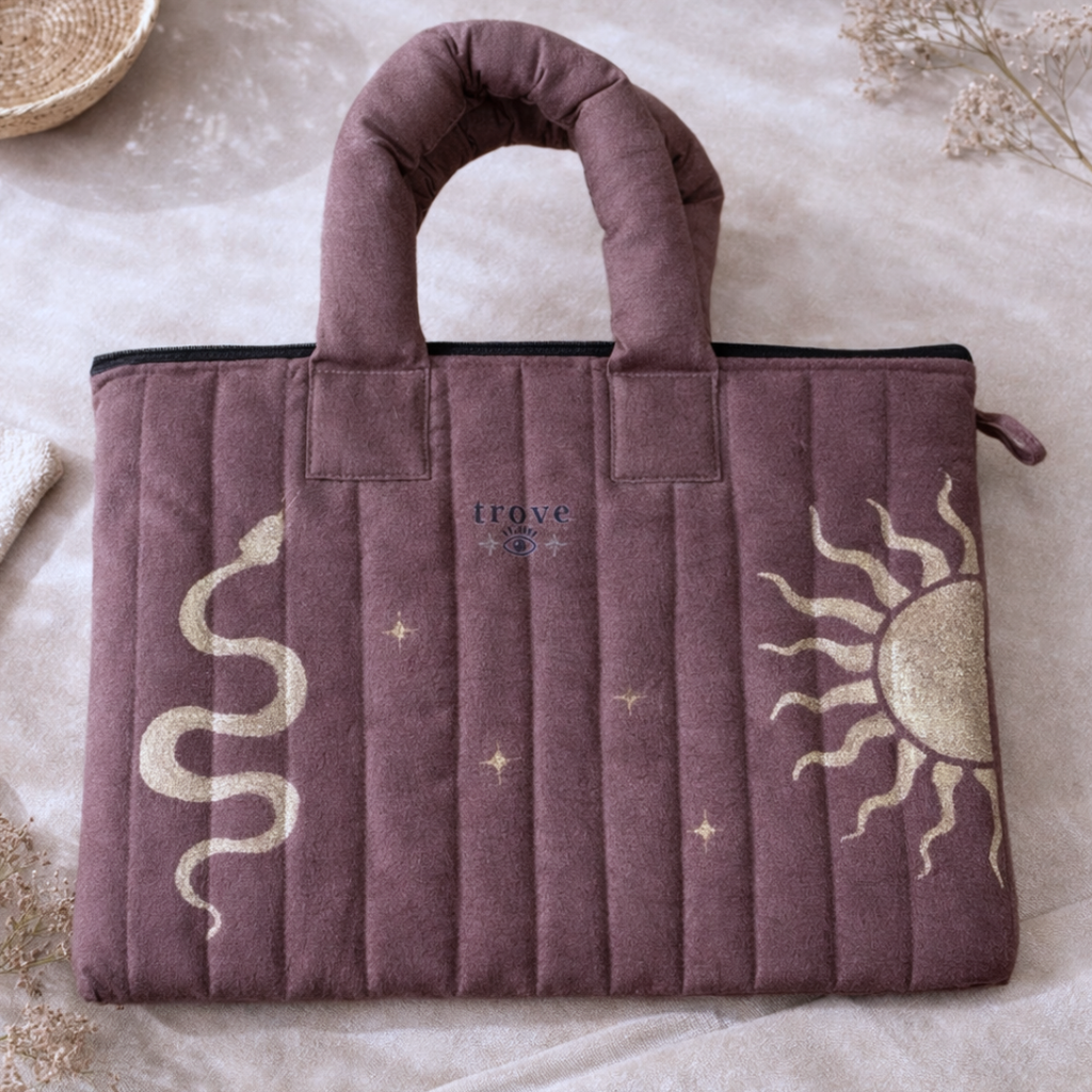 Purple bag with sun and snake designs on a textured surface