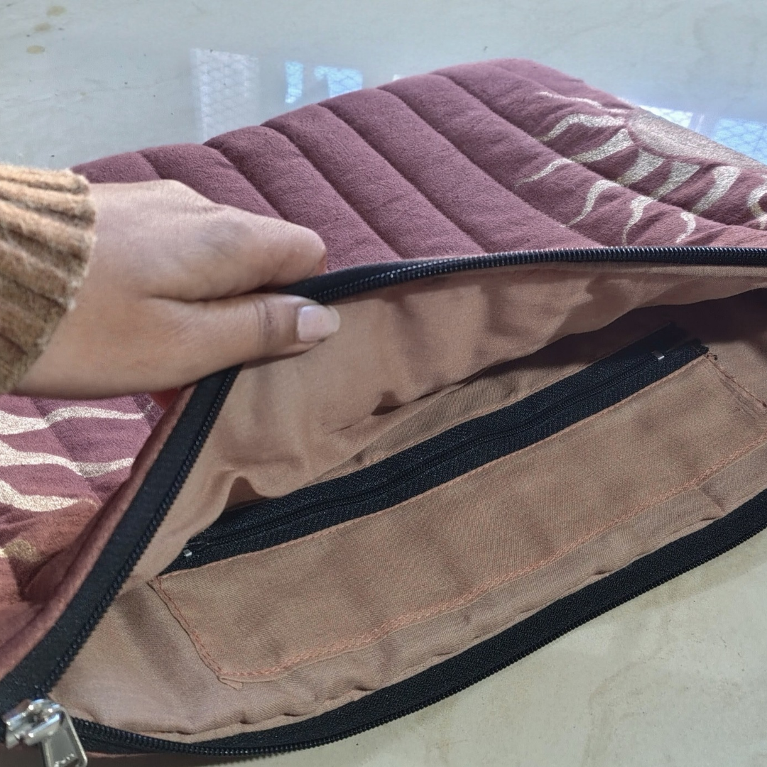 Close-up of a quilt with a zipper, held by a person's hand.