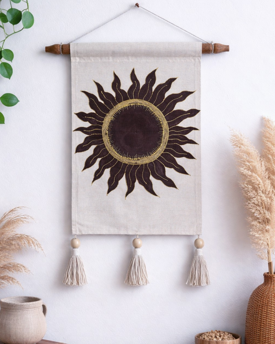 Decorative wall hanging with sun design and tassels on a white wall. Hand painted room decor