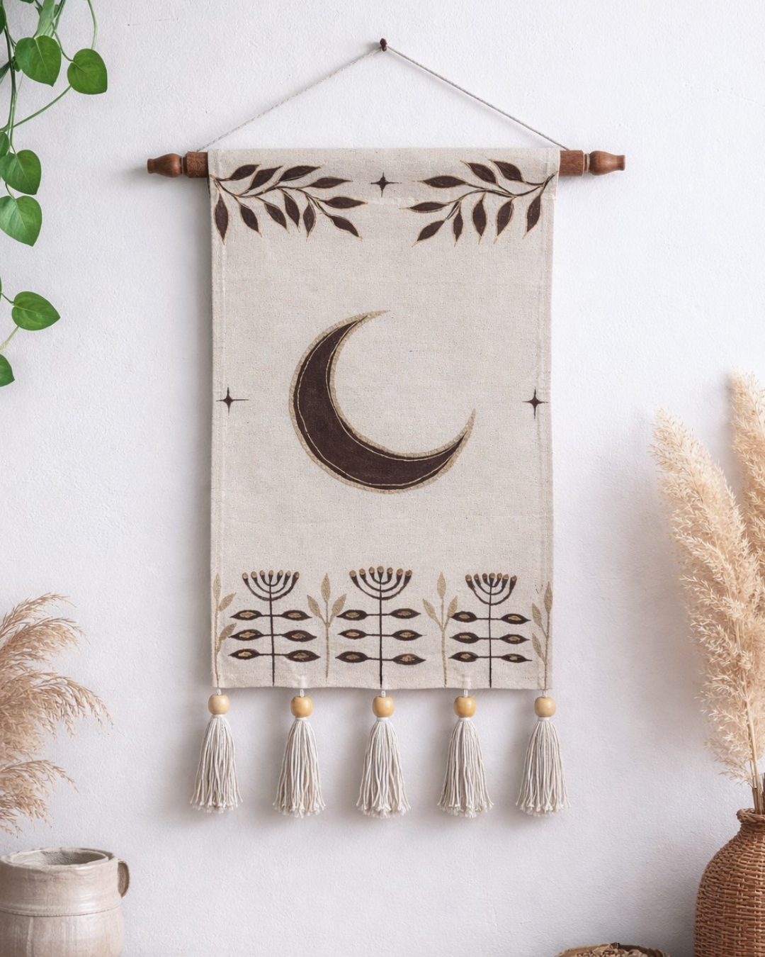 Decorative wall hanging with a moon design and tassels on a white wall. Hand painted room decor luxury good for gifting