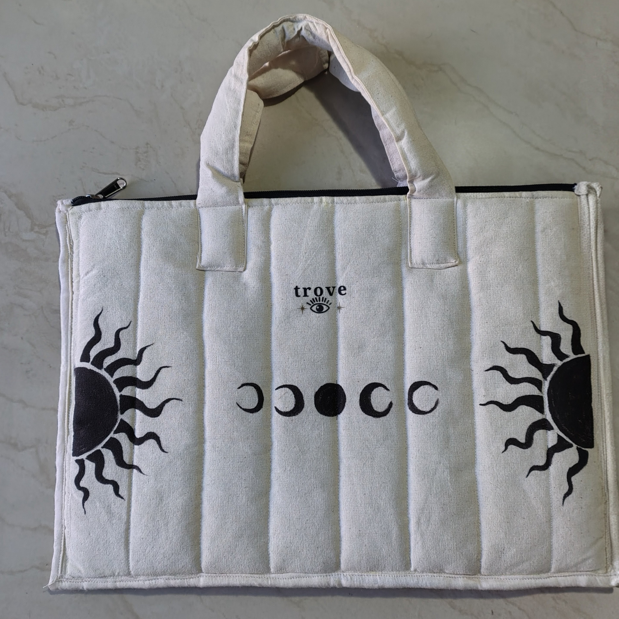 White tote bag with black sun and moon designs and 'trove' branding on a light gray background, fluffy and puffy laptop bag for office and college purpose.